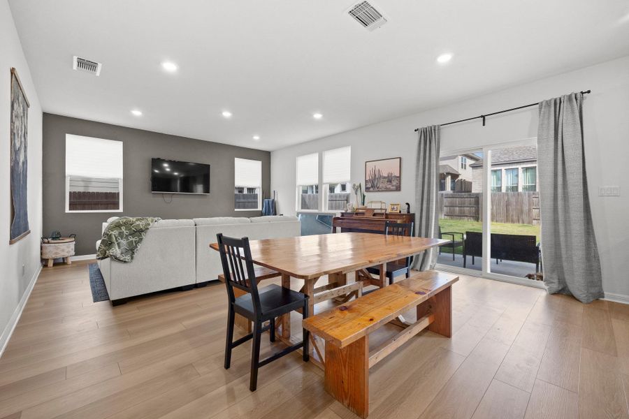 Open-concept living space featuring wood-finish flooring, recessed lighting, and a sliding glass door leading to the backyard