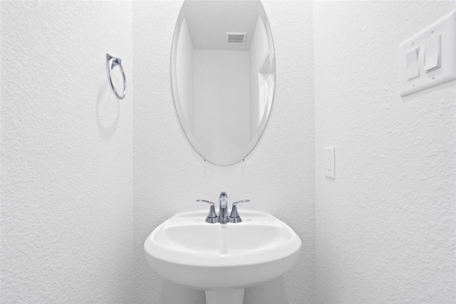 The powder room on the first floor includes a pedestal sink, mirror, and toilet to conveniently meet your needs. The powder room on the first floor includes a pedestal sink, mirror, and toilet to conveniently meet your needs.