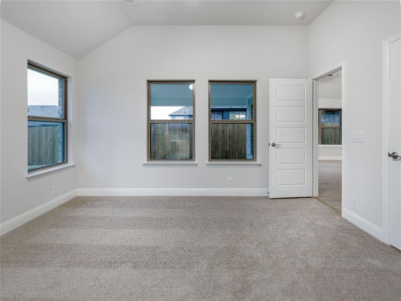 Empty room with light carpet and vaulted ceiling