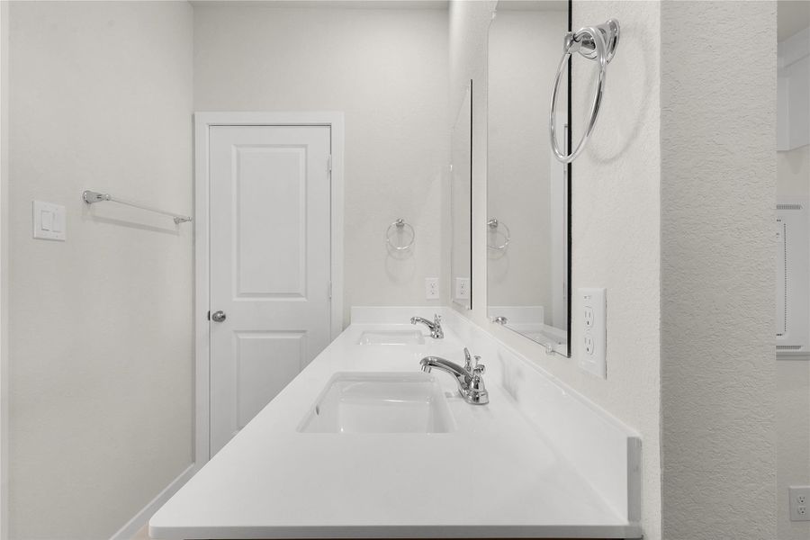 Full bath with double vanity and a textured wall