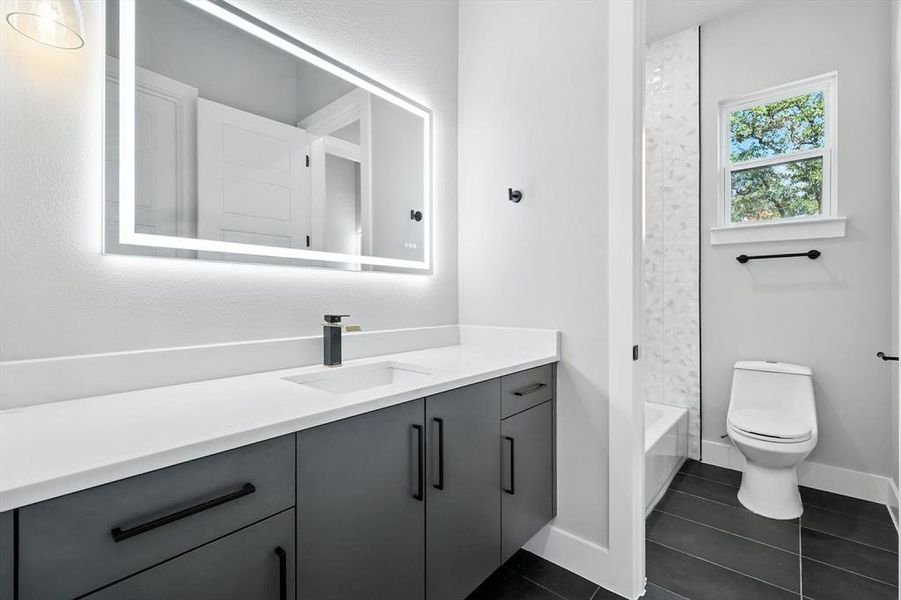 Bathroom with vanity, dark tile patterned flooring, and tub / shower combination Bathroom with vanity, dark tile patterned flooring, and tub / shower combination