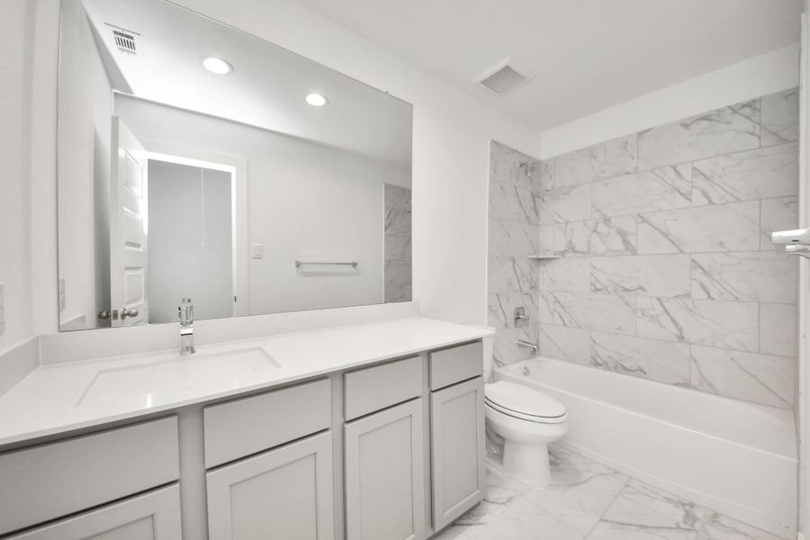 Secondary bath features tile flooring, bath/shower combo with tile surround, light stained wood cabinets, beautiful light countertop. Secondary bath features tile flooring, bath/shower combo with tile surround, light stained wood cabinets, beautiful light countertop.