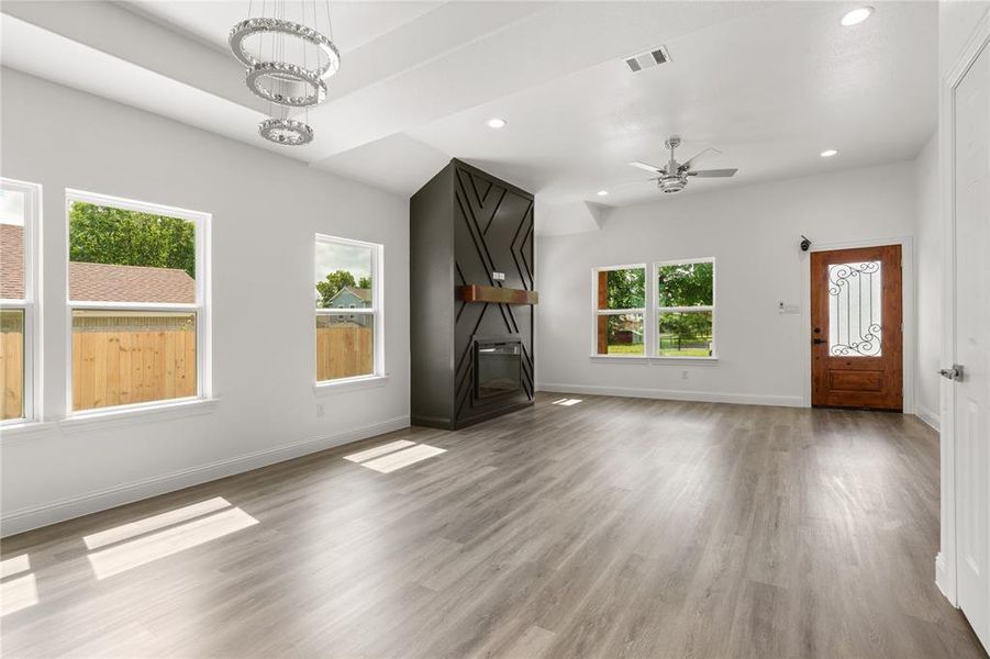 Spacious living area featuring wood-finish flooring, a vaulted ceiling, and an ornate dark wood front door