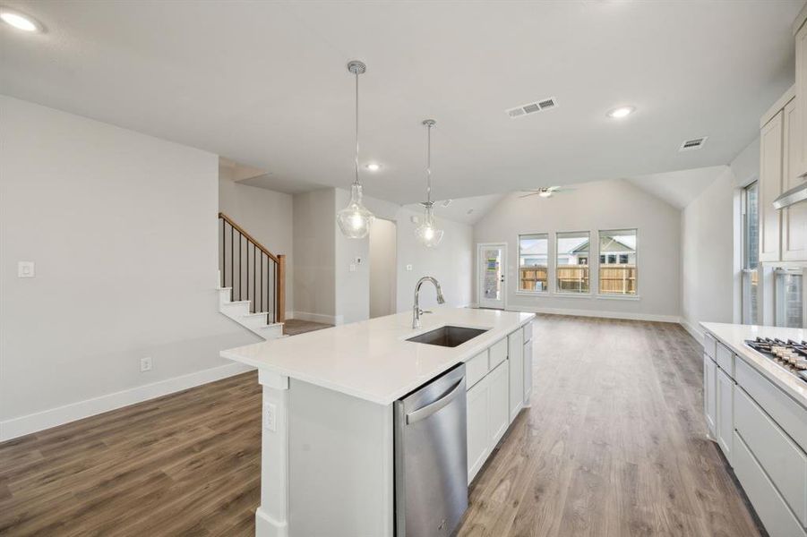 Kitchen with lofted ceiling, a center island with sink, sink, appliances with stainless steel finishes, and white cabinetry