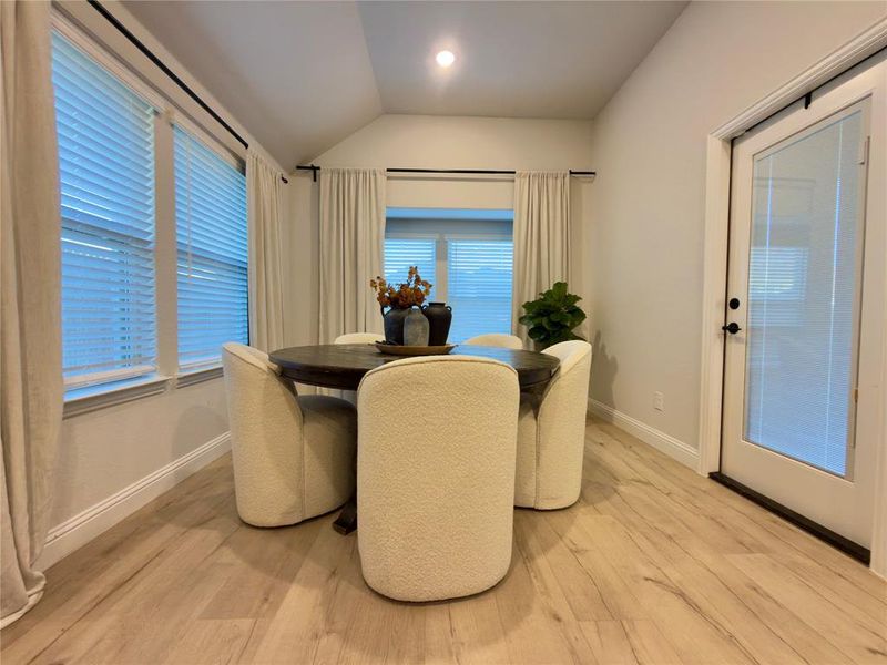 Dining space with light wood-type flooring, vaulted ceiling, and recessed lighting