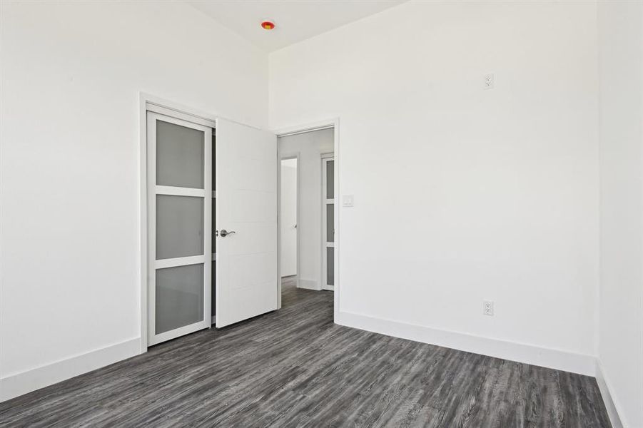 Spare room featuring dark wood-style floors and baseboards