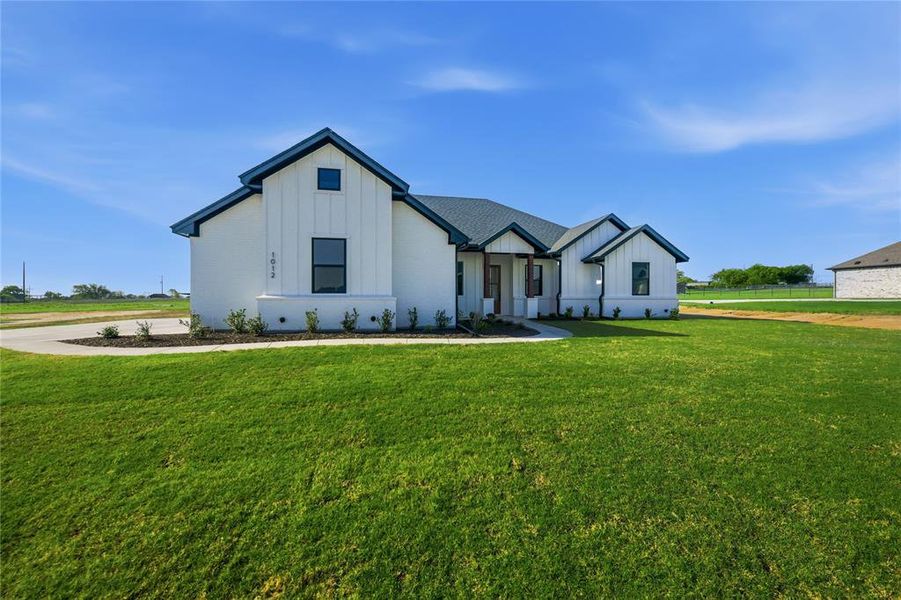 Modern inspired farmhouse with board and batten siding and a front yard Modern inspired farmhouse with board and batten siding and a front yard