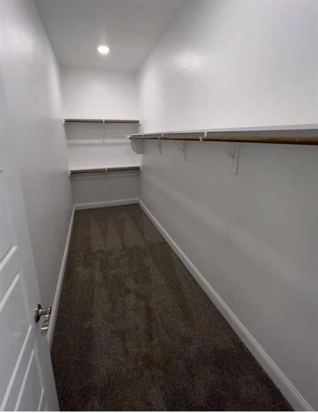 Spacious closet 1 in primary suite  with painted shelves and wood rods