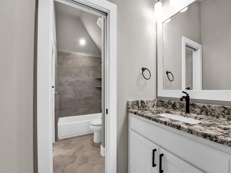 Bathroom featuring vanity,  shower combination, a textured wall, and light tile patterned flooring