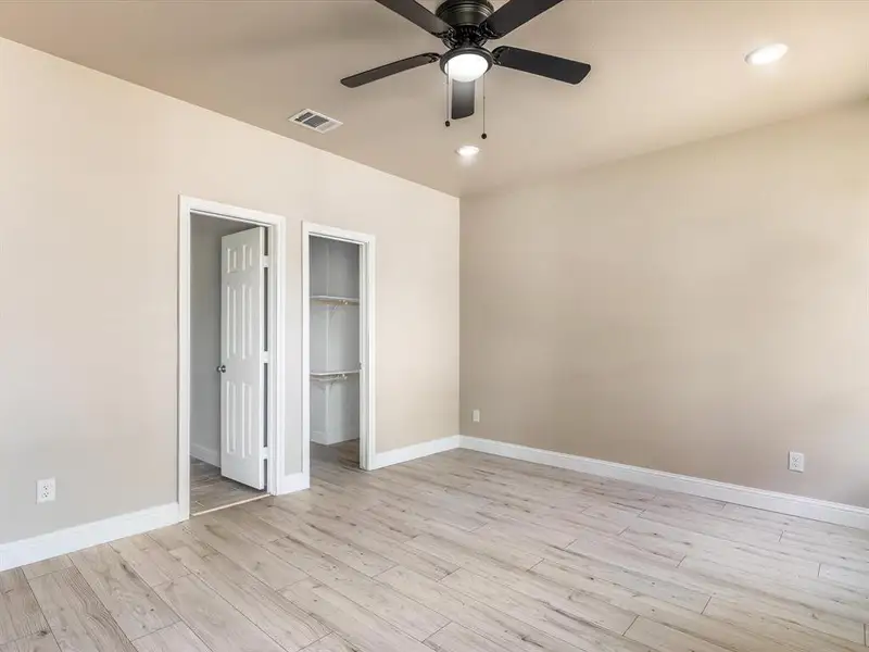 Unfurnished bedroom featuring light wood-style flooring, a walk in closet, recessed lighting, a ceiling fan, and a closet Unfurnished bedroom featuring light wood-style flooring, a walk in closet, recessed lighting, a ceiling fan, and a closet