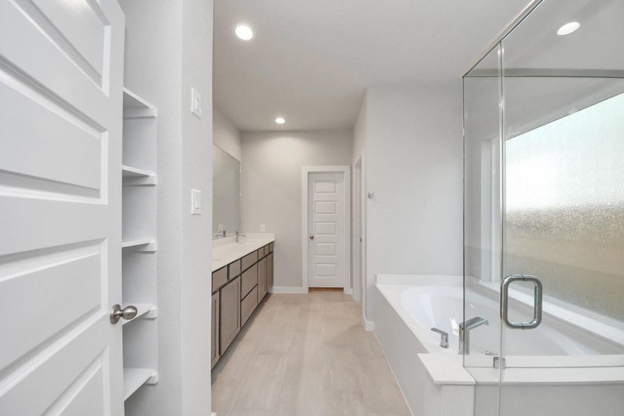 Escape to a spa-like oasis in this primary bathroom. Enjoy a walk-in shower with tile surround, a separate garden tub with custom detailing, and an elegant vanity featuring light countertops, modern hardware, and beautiful recessed lights. Experience luxury and relaxation in every detail. v