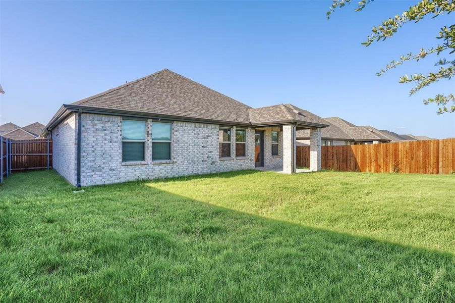 Rear view of property featuring a fenced backyard, brick siding, and roof with shingles Rear view of property featuring a fenced backyard, brick siding, and roof with shingles