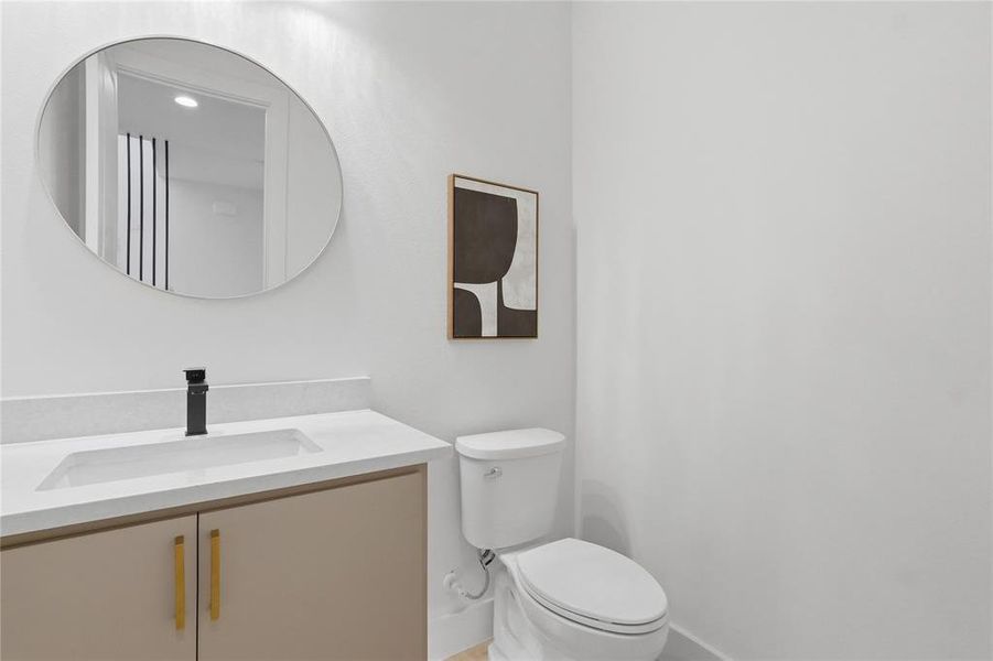 Powder room featuring a single vanity with a flat-panel cabinet and gold-tone hardware, a white undermount sink, and a black single-handle faucet Powder room featuring a single vanity with a flat-panel cabinet and gold-tone hardware, a white undermount sink, and a black single-handle faucet