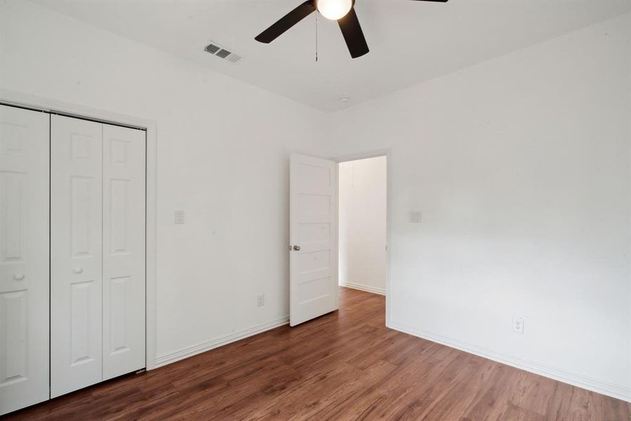 Unfurnished bedroom featuring dark hardwood / wood-style flooring, ceiling fan, and a closet