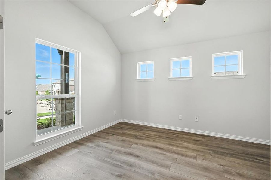 Empty room with ceiling fan, wood finished floors, and lofted ceiling