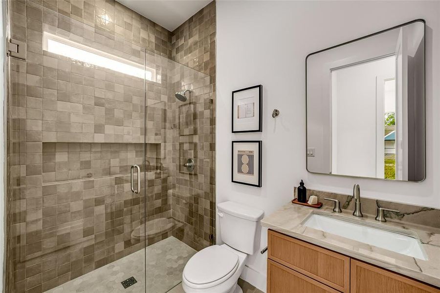 Modern bathroom featuring a glass-enclosed shower with square tile walls and a recessed niche