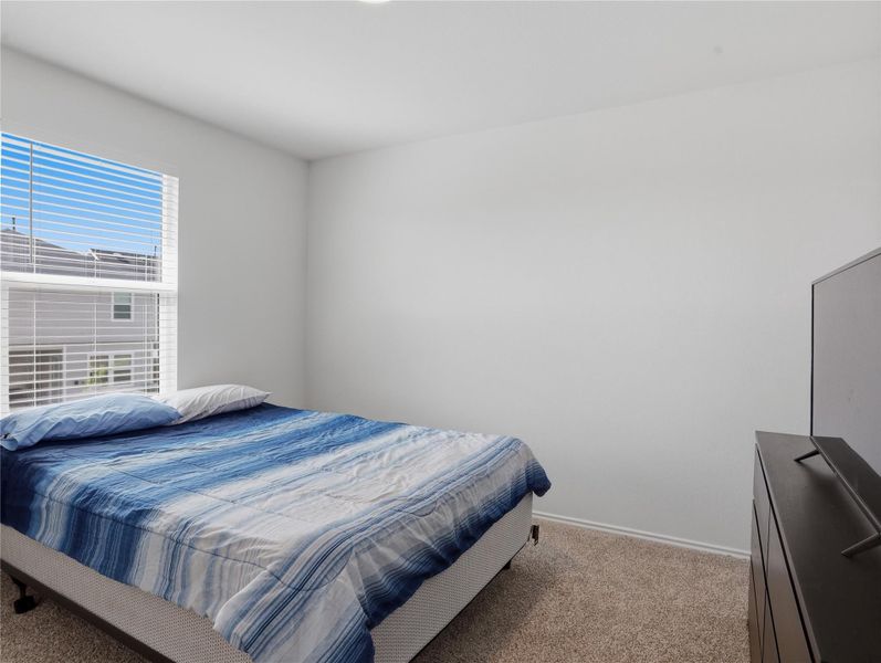 A window fills this carpeted bedroom with natural light. A window fills this carpeted bedroom with natural light.