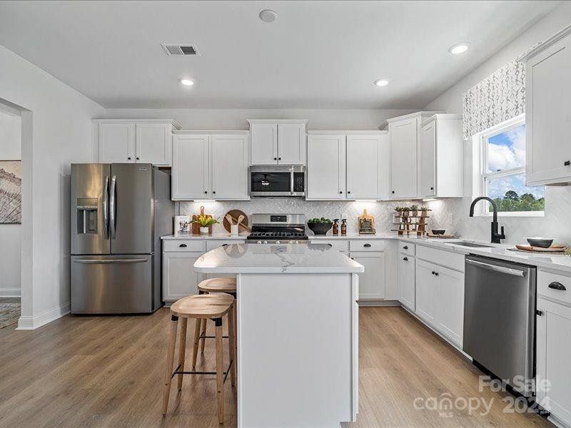 PHOTO REPRESENTATION ONLY. Kitchen of decorated model home. Finishes are different than shown. Refer to the interior design selections for finishes. Refrigerator not included.