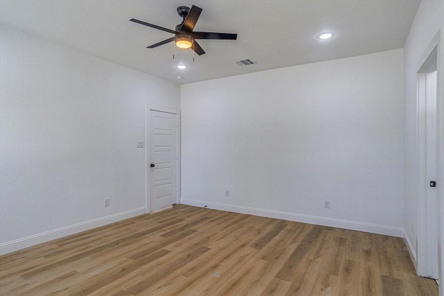 Empty room with light hardwood / wood-style floors and ceiling fan