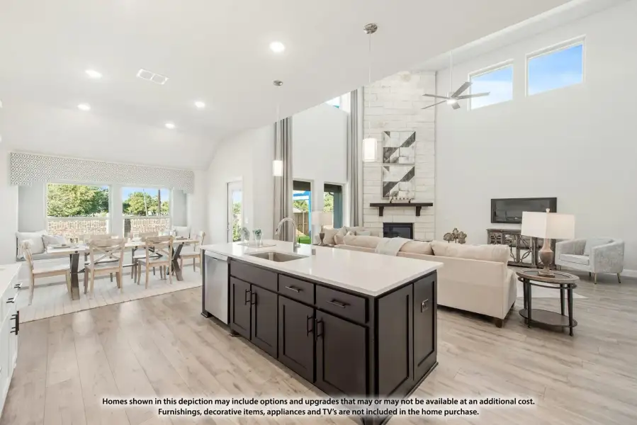 Open-concept kitchen with dark island, vaulted ceiling, and adjoining living and dining areas with stone fireplace.