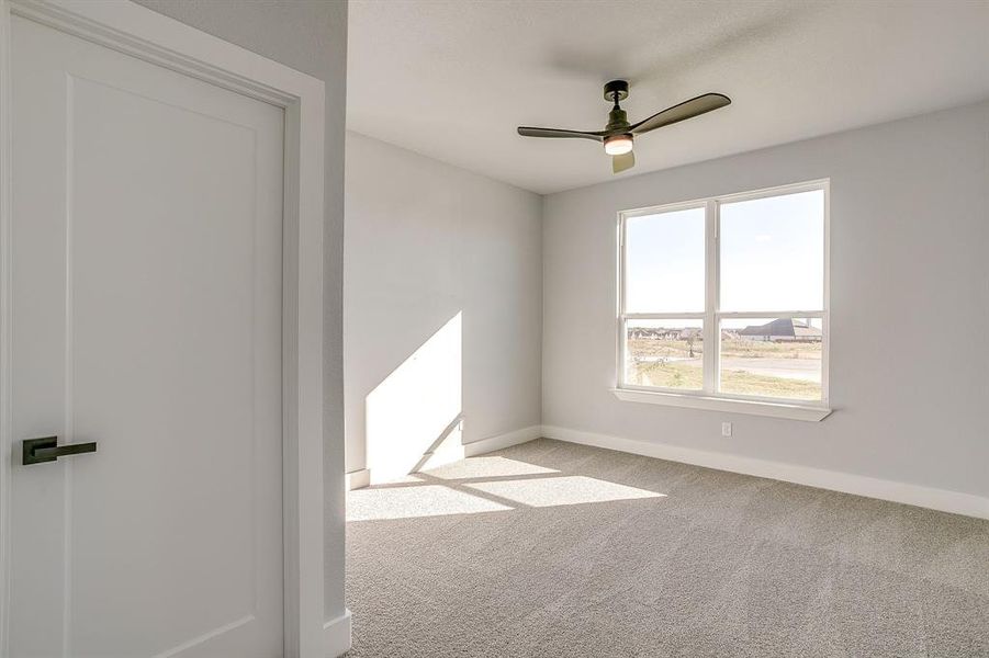 Carpeted spare room featuring baseboards and ceiling fan