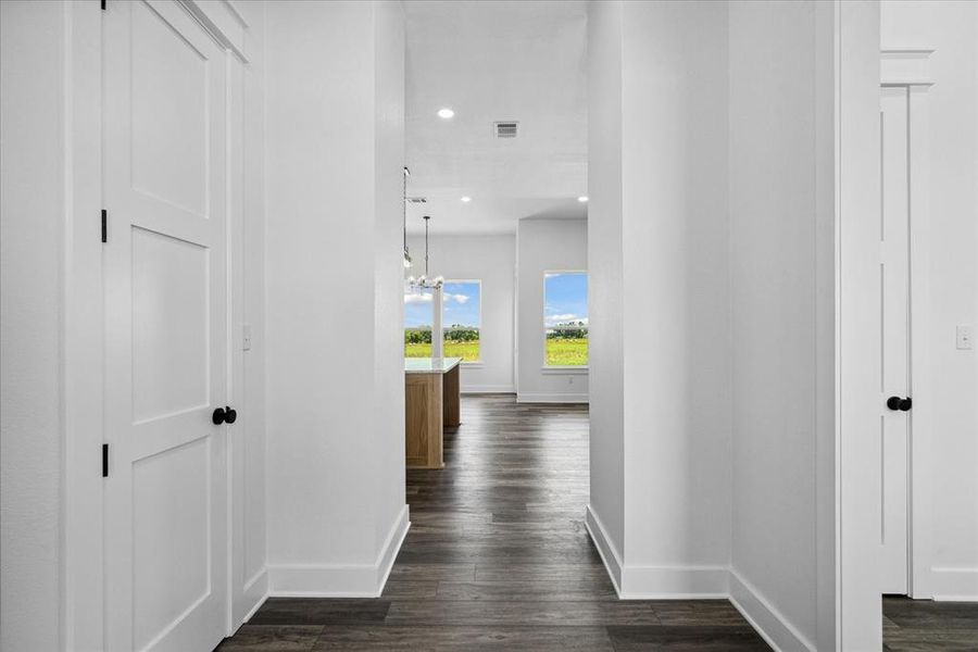 Hall featuring dark wood-type flooring, recessed lighting, and a chandelier