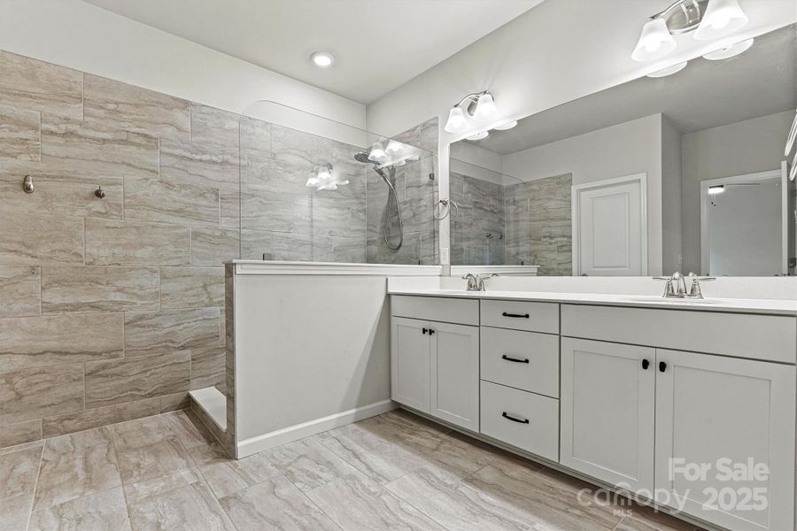 Step into the luxurious primary ensuite featuring dual sinks, a spacious walk-in tiled shower, elegant tile flooring, and direct access to the generous walk-in closet—designed for both comfort and style. Step into the luxurious primary ensuite featuring dual sinks, a spacious walk-in tiled shower, elegant tile flooring, and direct access to the generous walk-in closet—designed for both comfort and style.