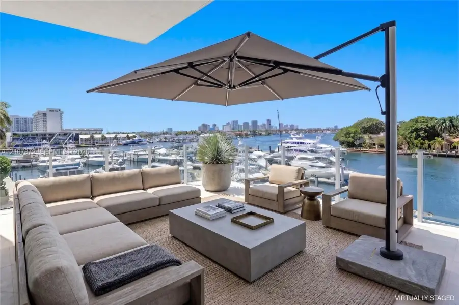 Expansive outdoor terrace featuring light-toned stone tile flooring and a glass panel railing Expansive outdoor terrace featuring light-toned stone tile flooring and a glass panel railing