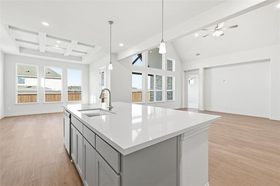 Kitchen with open floor plan, gray cabinetry, beam ceiling, light wood-style floors, and pendant lighting Kitchen with open floor plan, gray cabinetry, beam ceiling, light wood-style floors, and pendant lighting
