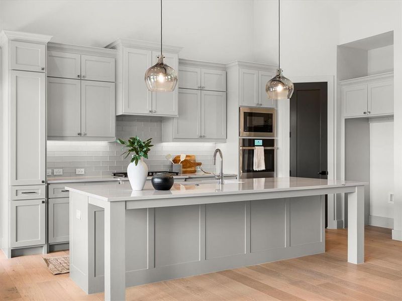 Kitchen featuring decorative backsplash, pendant lighting, light wood-style flooring, and oven Kitchen featuring decorative backsplash, pendant lighting, light wood-style flooring, and oven