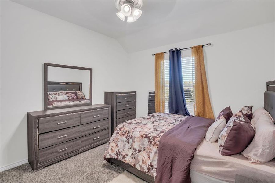 Carpeted bedroom with ceiling fan and lofted ceiling