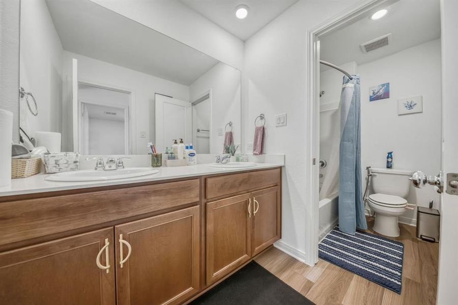 Dual sink vanity with a white countertop and wood-finish cabinetry Dual sink vanity with a white countertop and wood-finish cabinetry
