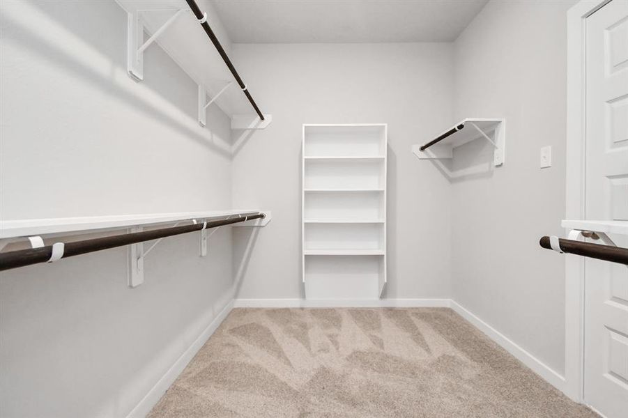 Spacious walk-in closet with high ceilings and plush carpet.  Sample photo of completed home with similar plan. As built color and selections may vary.