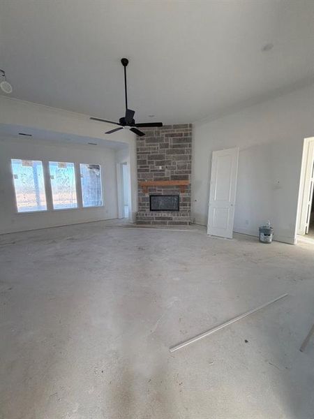 Unfurnished living room with a fireplace, unfinished concrete floors, and a ceiling fan