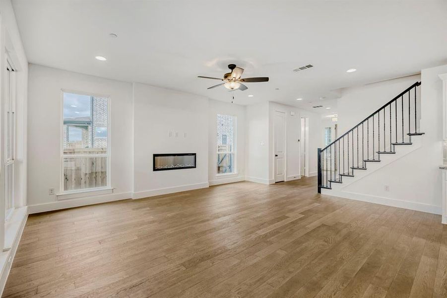 Spacious living area featuring wood-finish flooring, a contemporary electric fireplace, recessed lighting, and a ceiling fan