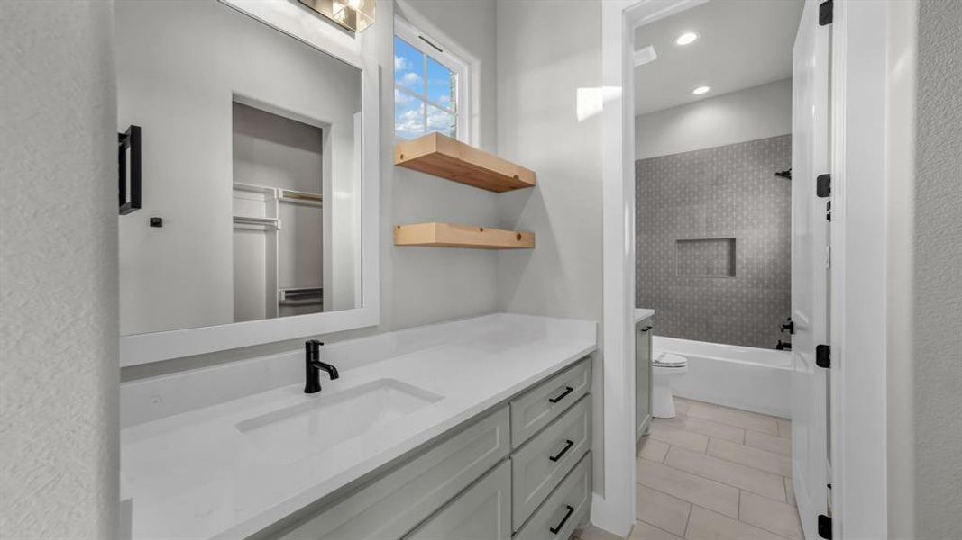 Bathroom vanity featuring a light grey cabinet with black hardware, white countertop with integrated sink, and matte black faucet Bathroom vanity featuring a light grey cabinet with black hardware, white countertop with integrated sink, and matte black faucet