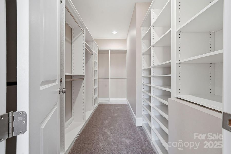 Expansive custom walk-in closet with built-in shelving and ample storage. Expansive custom walk-in closet with built-in shelving and ample storage.
