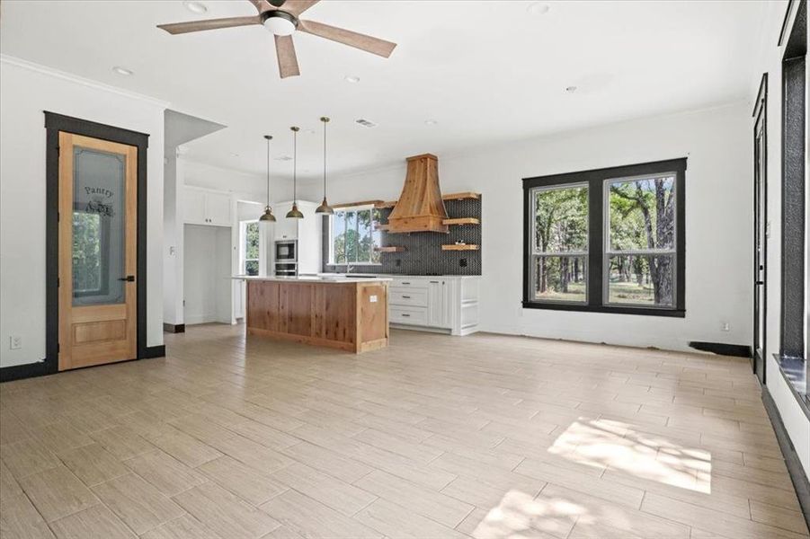 Kitchen with white cabinets, open shelves, tasteful backsplash, hanging light fixtures, and light wood-style flooring