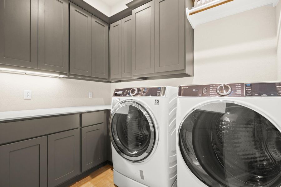 Washroom featuring washing machine and dryer, cabinet space, and light wood-style flooring Washroom featuring washing machine and dryer, cabinet space, and light wood-style flooring