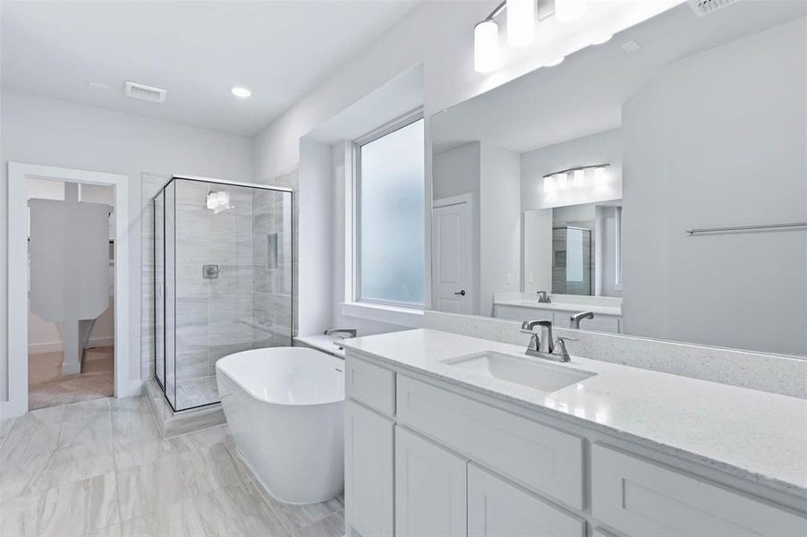 Primary bathroom featuring a soaking tub, separate walk-in shower, and bright neutral finishes.