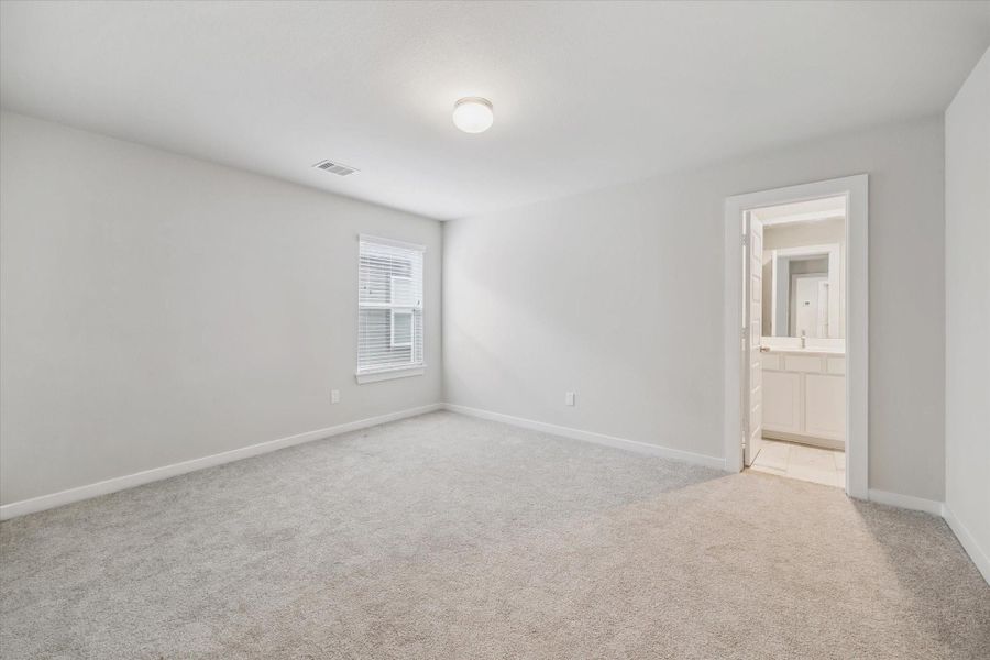 Bright, spacious bedroom with soft carpeting, neutral walls, a window for natural light, and an en-suite bathroom. Bright, spacious bedroom with soft carpeting, neutral walls, a window for natural light, and an en-suite bathroom.