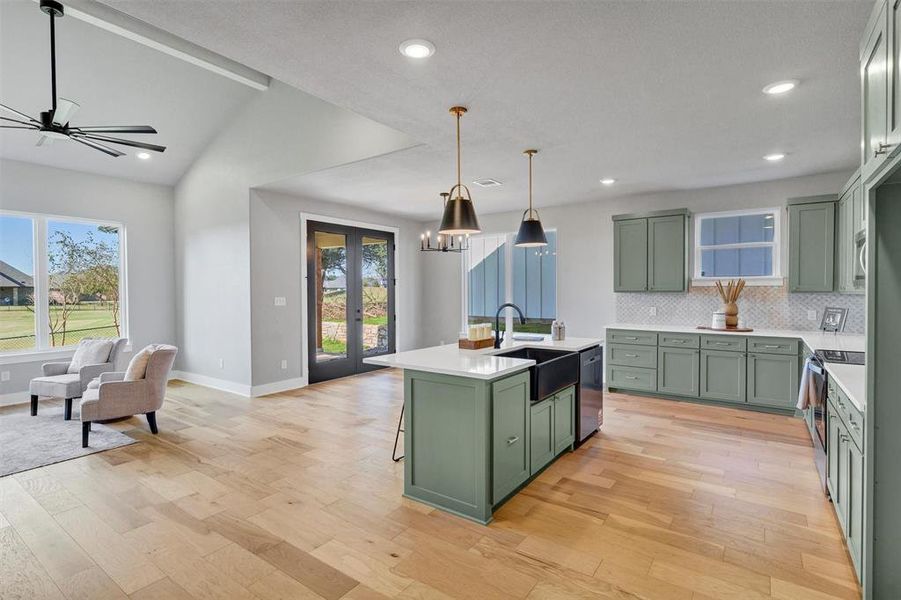 Kitchen with green cabinetry, a center island with sink, light wood-style flooring, a breakfast bar area, and recessed lighting Kitchen with green cabinetry, a center island with sink, light wood-style flooring, a breakfast bar area, and recessed lighting