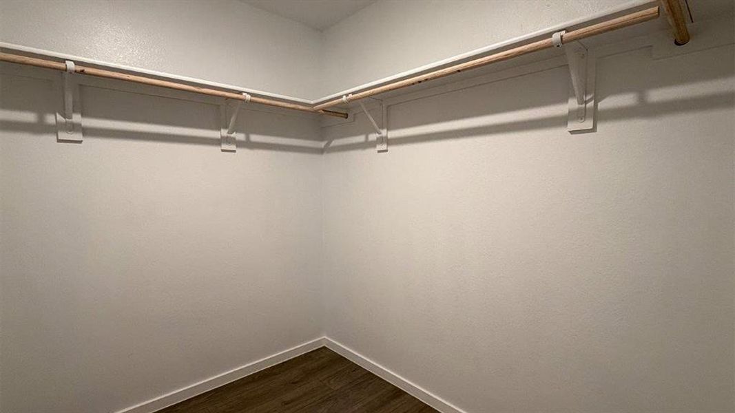 Walk-in closet featuring light wood-finish flooring, white baseboards, and neutral wall paint Walk-in closet featuring light wood-finish flooring, white baseboards, and neutral wall paint