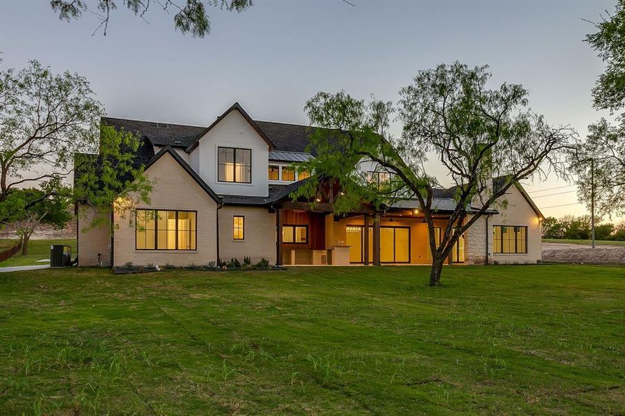 Back of house featuring a yard, brick siding, and a patio