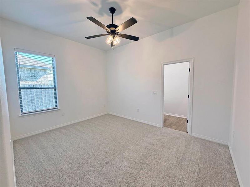 Empty room with light colored carpet and a ceiling fan