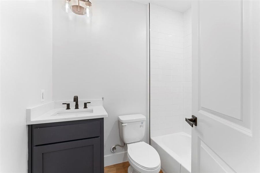 Bathroom featuring vanity, shower / bath combination, and wood finished floors Bathroom featuring vanity, shower / bath combination, and wood finished floors