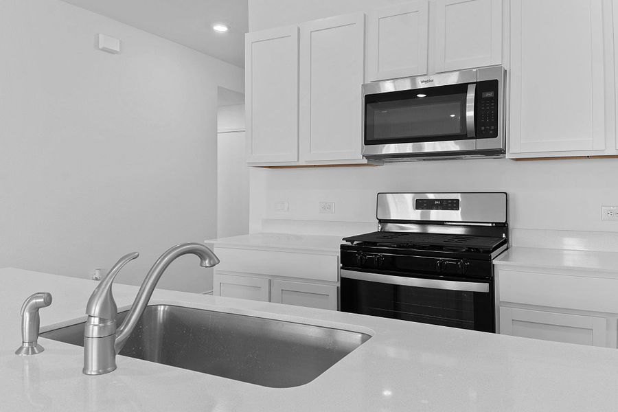 Kitchen with light countertops, appliances with stainless steel finishes, a sink, and white cabinetry