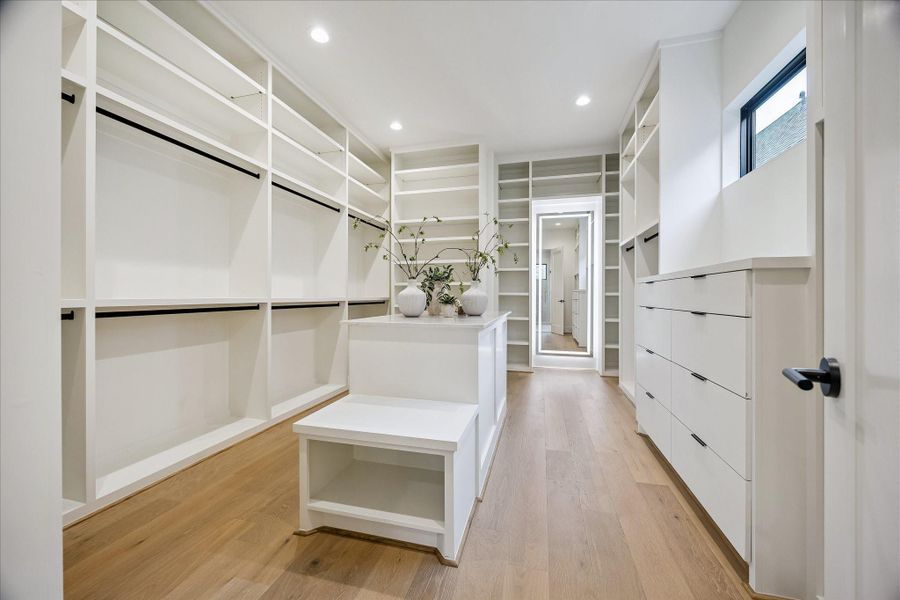 Primary closet – offers custom built-ins including an island, drawers, and a full-length mirror with back lighting. Primary closet – offers custom built-ins including an island, drawers, and a full-length mirror with back lighting.