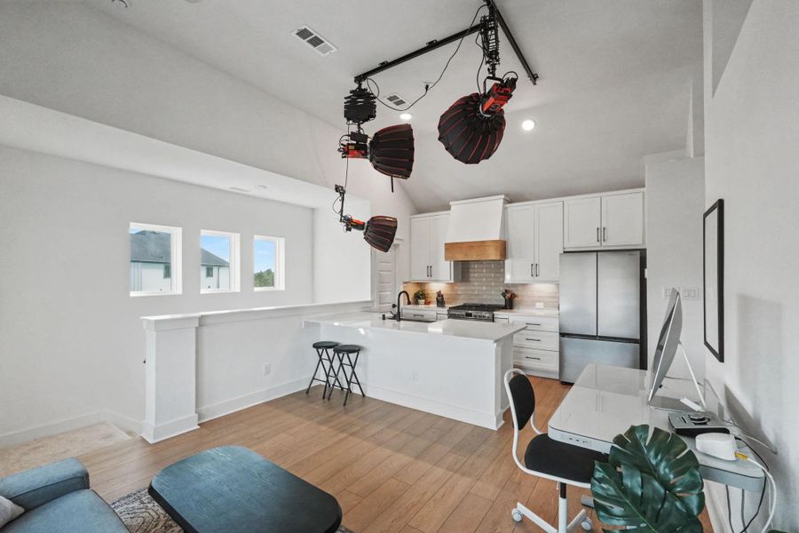 Stylish garage apartment featuring a designer kitchen with quartz countertops, stainless steel appliances, custom cabinetry, and a spacious breakfast bar. Soaring ceilings and abundant natural light create a bright, modern living space ideal for guests, family, or a private home office.