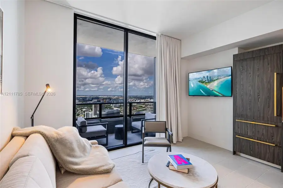 Floor-to-ceiling windows, private balcony, and custom floor-to-ceiling dark wood-finish cabinetry with metallic pulls